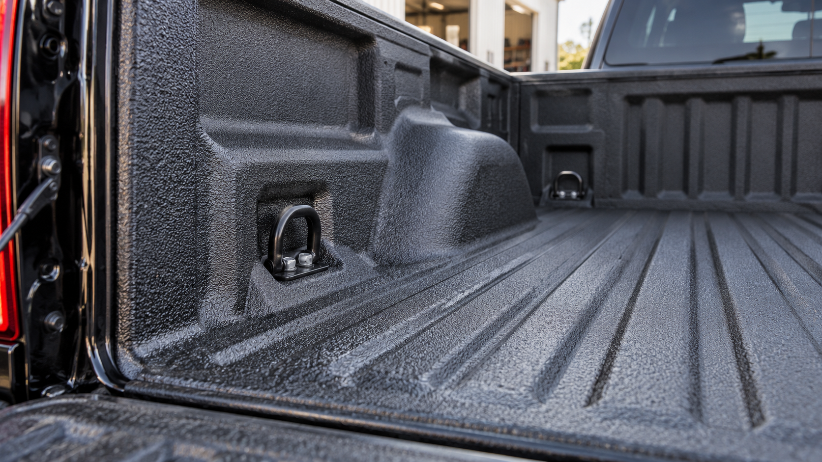 Tie-down anchors visible in an empty pickup bed with a textured spray-in liner.